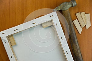 Hammer, wooden spacers a tool for stretching canvas onto a frame in an art workshop. The artist is preparing a canvas for painting