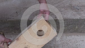 Hammering nail in wooden bird house nesting-box