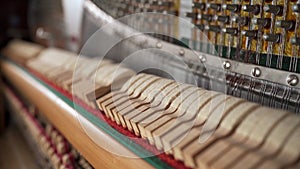 Hammers and strings inside piano, close up. Hammer in action, piano key is pressed.