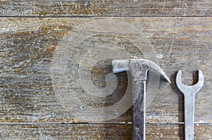 Old hammer and wrench on old wood background