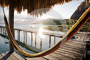 Hammock at dock during sunset with sun beam at lake Itza, El Remate, Peten, Guatemala