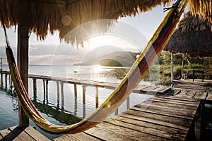 Hammock at dock during sunset with sun rays at lake Itza, El Remate, Peten, Guatemala