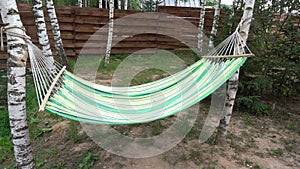 A hammock is hanging in a summer blooming garden in the backyard
