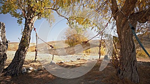 Hammock Hanging Between Two Trees With Dry Summer Landscape With Hills And Yellow Grass On Background
