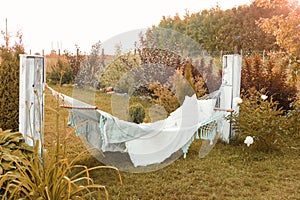 A hammock with pillows and a blanket on the street in the courtyard of a village house. A place to relax in the country