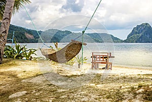 A hammock between two palm trees on the beach. Beautiful beach. The concept of rest and recreation. Beautiful tropical island.