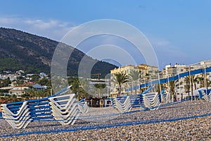 Hammocks stacked on Albir beach at sunrise