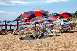 Hammocks and umbrellas on the beach with golden sand and blue sky in summer, Spain.