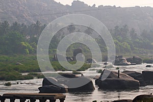 Hampi village Tungabhadra river meadow. Landscape with water, palm, rock, stones. India, Karnataka