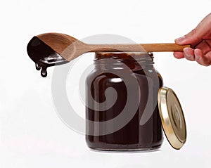 Han holding melted chocolate wood spoon over glass chocolate cream container