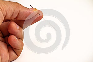 Hand of an acupuncturist holding a long thin acupuncture needle. Man`s hand and metal needle