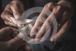 Hand of addict man with money buying dose of cocaine or heroine or another narcotic from drug dealer. Drug abuse and traffic