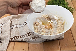 Hand adding flour to minced chicken with egg during cooking preparation process