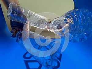 Hand is adding plastic bottles to recycling bin