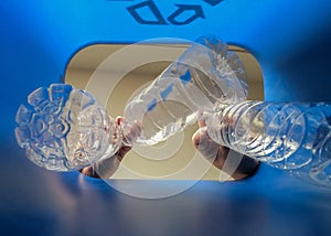 Hand is adding plastic bottles to recycling bin