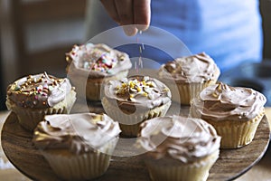 Hand adding sprinkles to chocolate cupcake food photography recipe idea