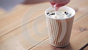 Hand adding and stirring sugar in cup of coffee