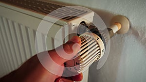 Hand adjusting temperature of radiator. Man turns regulator knob in radiator thermostat