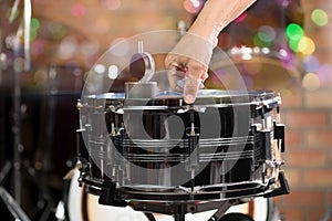 Hand adjusting tension rod of snare drum.