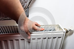 Hand adjusting thermostat valve of heating radiator in a room. Close up heating radiator. Central heating concept, radiator heater