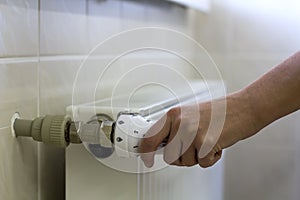 Hand adjusting the valve knob thermostat of heating radiator