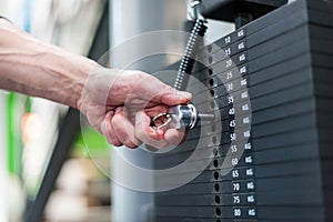 Hand adjusting weights in fitness center