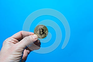 Hand of an adult holds bitcoin coin.