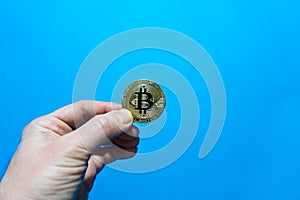 hand of an adult holds bitcoin coin.