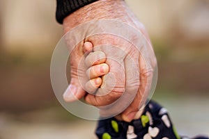 Hand of an adult man holding tightly child hand. Family connection, kid safety, protection and anti kidnap concept photo