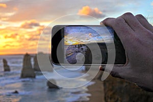 Hand of an adult man on vacation taking photos with a mobile pho