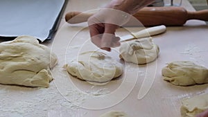 Hand of adult woman bakes pies from yeast dough woman right hand tosses piece of dough baking sheet white knife and