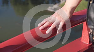 Hand of adult woman caressing top of red bridge in Japanese Garden
