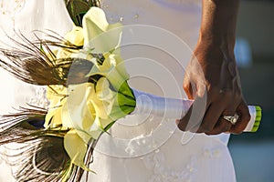 Hand of African American bride with wedding ring holding flower bouquet