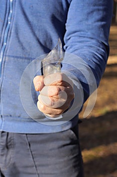 the hand of an aggressive male criminal in blue clothes holds a sharp piece of glass broken bottle