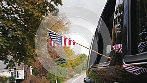A hand with an American flag looks out of the window of a traveling car. Slow Motion video