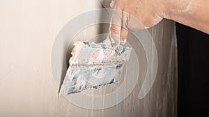 Hand application of wall putty with a spatula closeup, plaster repair work