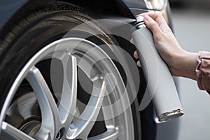 A hand applies a rubber blackener to a car wheel. Close up