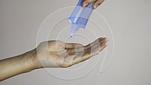 A hand apply alcohol gel from clear plastic bottle to another hand. Anti germ and preventative concept