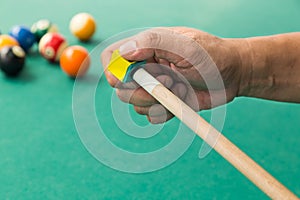 Hand applying chalk on tip of billards pool stick