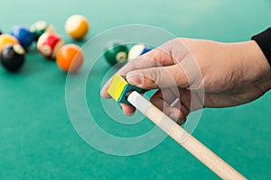 Hand applying chalk on tip of billards pool stick