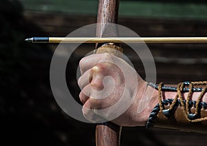 Hand of an archer holds bow and arrow and aims at target