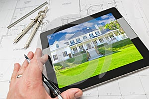 Hand of Architect on Computer Tablet Showing Home Photo Over Hou