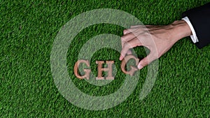 Hand arrange wooden alphabet text in GHG on biophilic background. Gyre