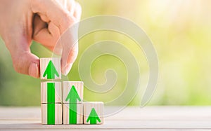 Hand arranging wood block stacking as step stair with arrow up. Ladder career path concept for business growth success process.