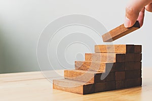 Hand arranging wood block stacking as step stair. Ladder career path concept for business growth success process