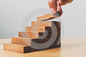 Hand arranging wood block stacking as step stair. Ladder career path concept for business growth success process