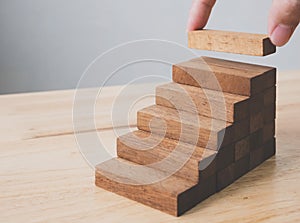 Hand arranging wood block stacking as step stair. Ladder career path concept for business growth success process, Copy space