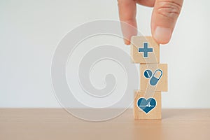 Hand arranging wood block stacking with healthcare medical icon, health insurance, wellness, wellbeing concept