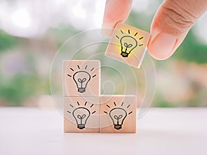 hand arranging wooden block with light bulb for leadership