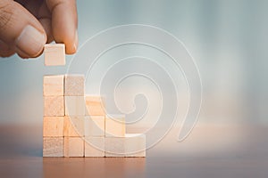 Hand arranging wooden block stacking as step stair. Business growth concept